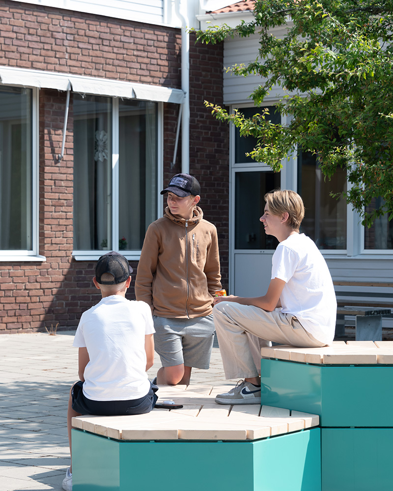 Boys hanging out on a Rosenlund seating group at their schoolyard.